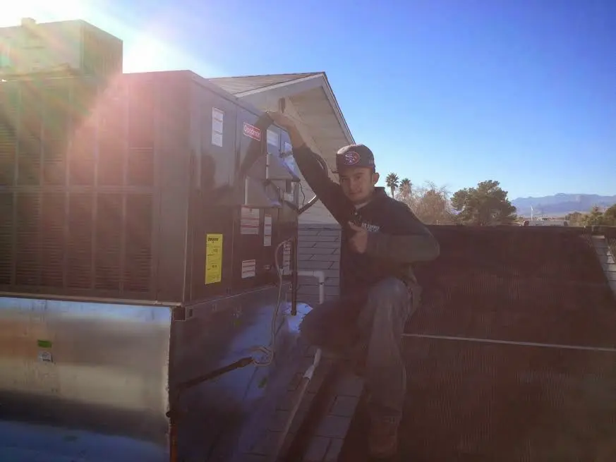HVAC technician performing Heat Pump Repair on a rooftop unit in Williamson